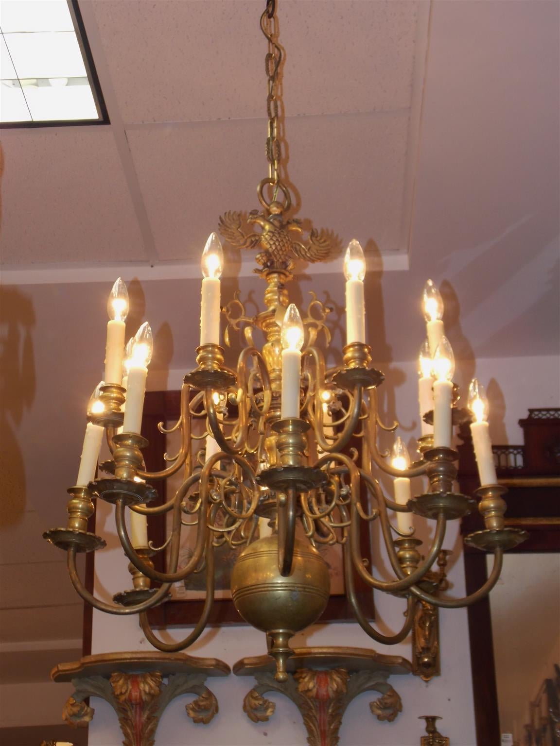 Prussian brass two-tiered sixteen-light chandelier with double eagle medallion, bulbous turned and ringed center column, scrolled arms with original bobeches, and terminating with a lower urn finial. Originally candle powered and has been