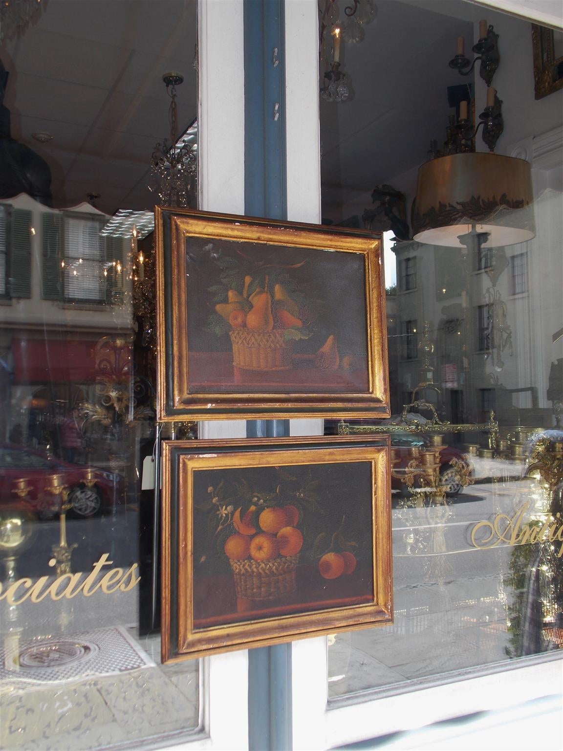 Coppia di alambicchi americani a olio su tela in cornici dorate e dipinte. Ogni quadro è composto da frutta in cesti di vimini.  Firmato dall'artista.  T. Maria.  Inizio del XIX secolo.