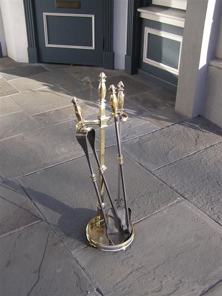 French brass and polished steel fire tools on stand with reeded floral finials, circular base, and terminating on ball feet. Set consist of tongs, shovel, and poker. Mid 19th Century