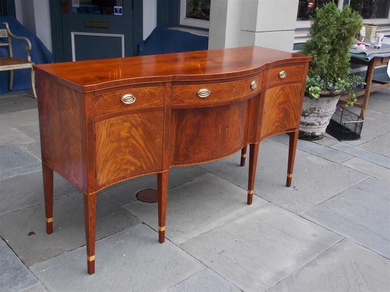 American Cherry serpentine sideboard with three upper drawers, three lower cupboards, oval and floral Holly string inlay, Heart Pine secondary, and terminating on squared tapered cuffed legs. Kentucky, Late 18th Century. Dealers please call for