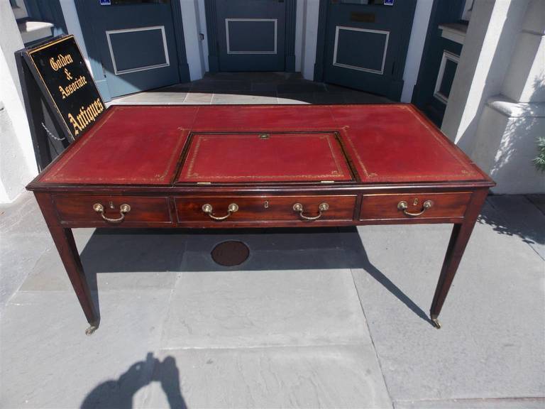 English Chippendale mahogany three drawer leather top writing desk with tilt writing surface, original brasses, and terminating on tapered legs with original brass casters.  Late 18th Century.  Table is finished on all sides.