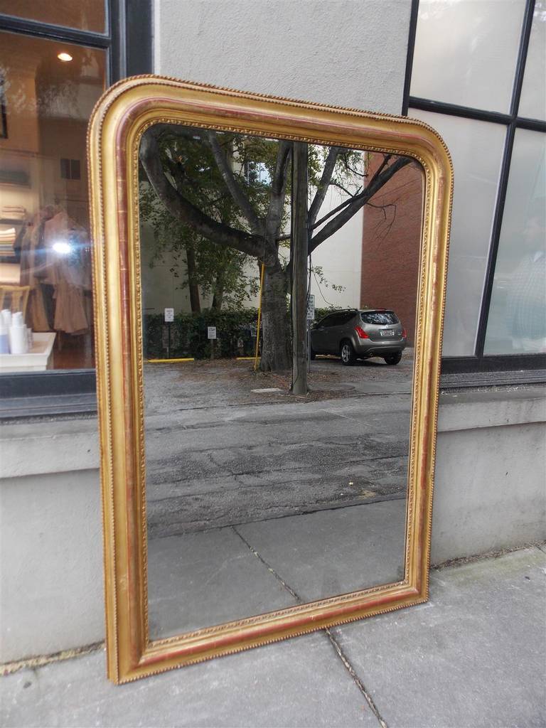 French gilt carved wood and gesso wall mirror with exterior rope and beaded molded edge, red lacquer, and interior carved floral motif. Mirror retains the original glass and wood back, Early 19th century.
