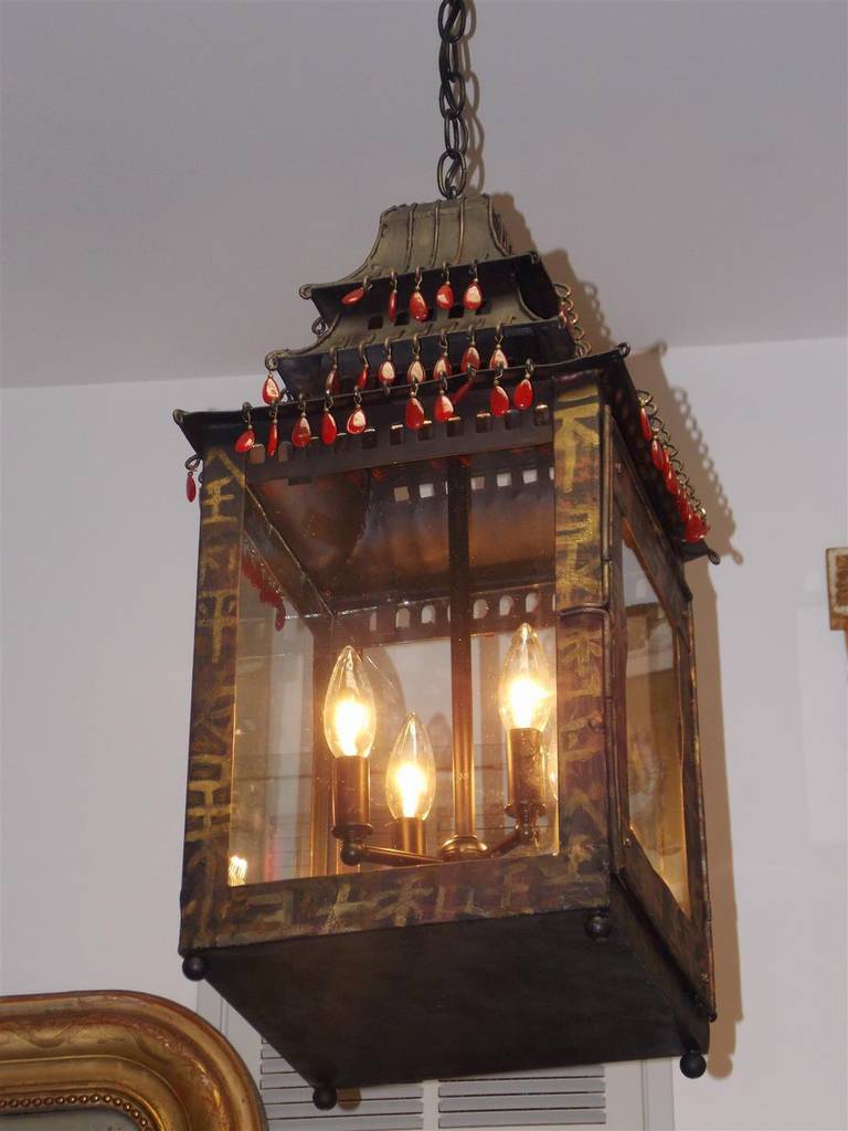French Tin hand-painted tole pagoda hanging lantern with tiered ruby pear-shaped prisms and interior four-light cluster. Originally candle powered and has been electrified, Mid-19th Century.