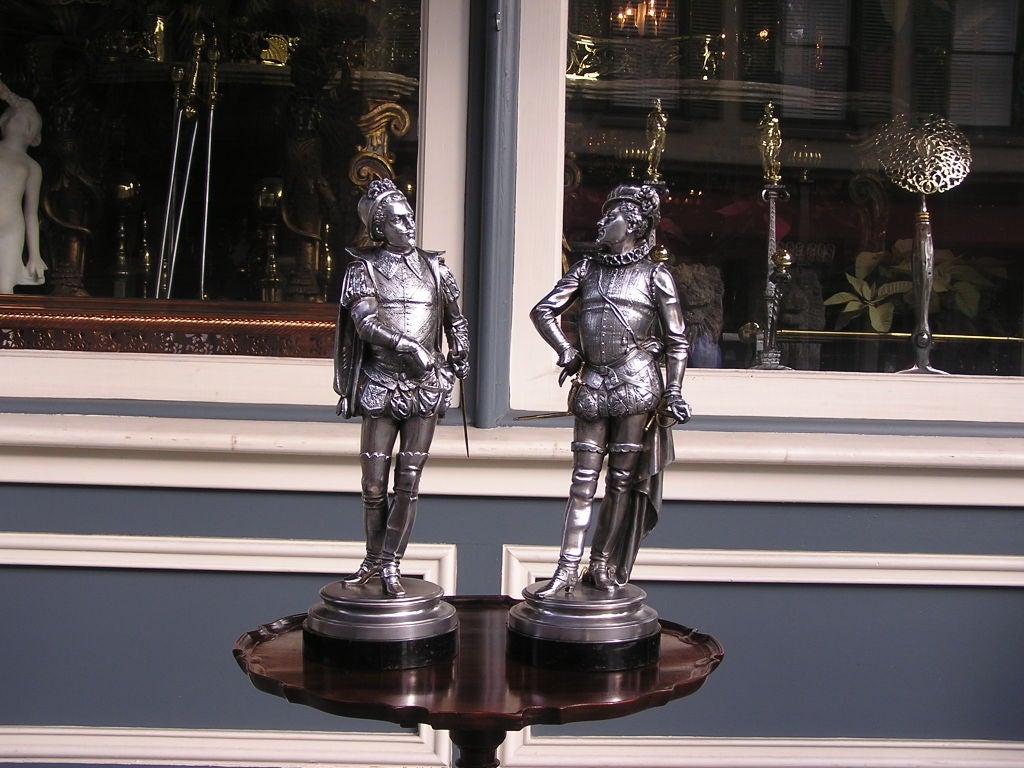 Pair of English spelterware cavaliers dressed in uniform attire with fighting swords and mounted on ebonized circular bases. Early 20th Century