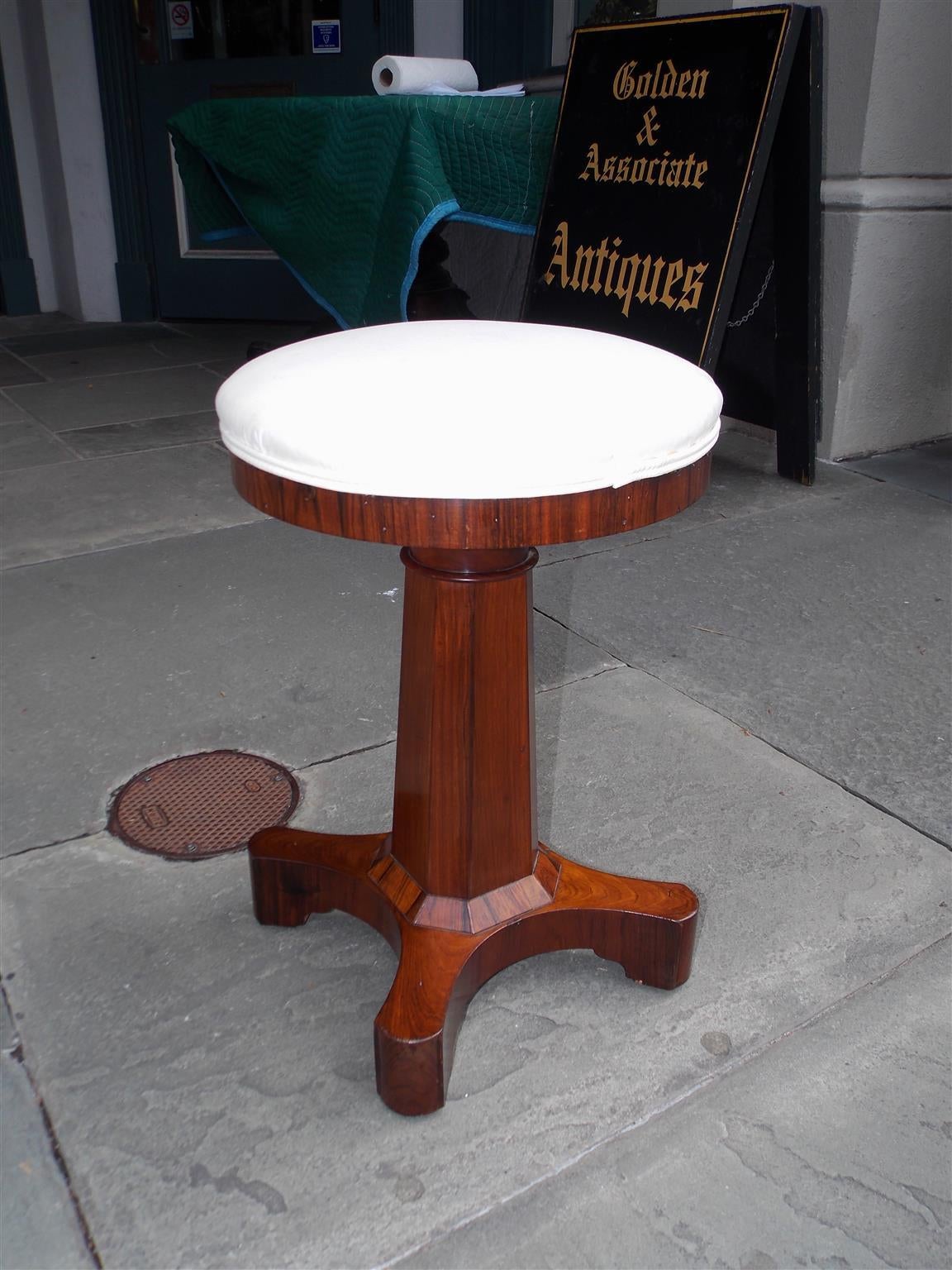 American Kings wood harp / piano stool with telescopic seat,  octagonal pedestal, and terminating on quad base with rounder block feet. Stool is upholstered in white muslin. Early 19th Century.