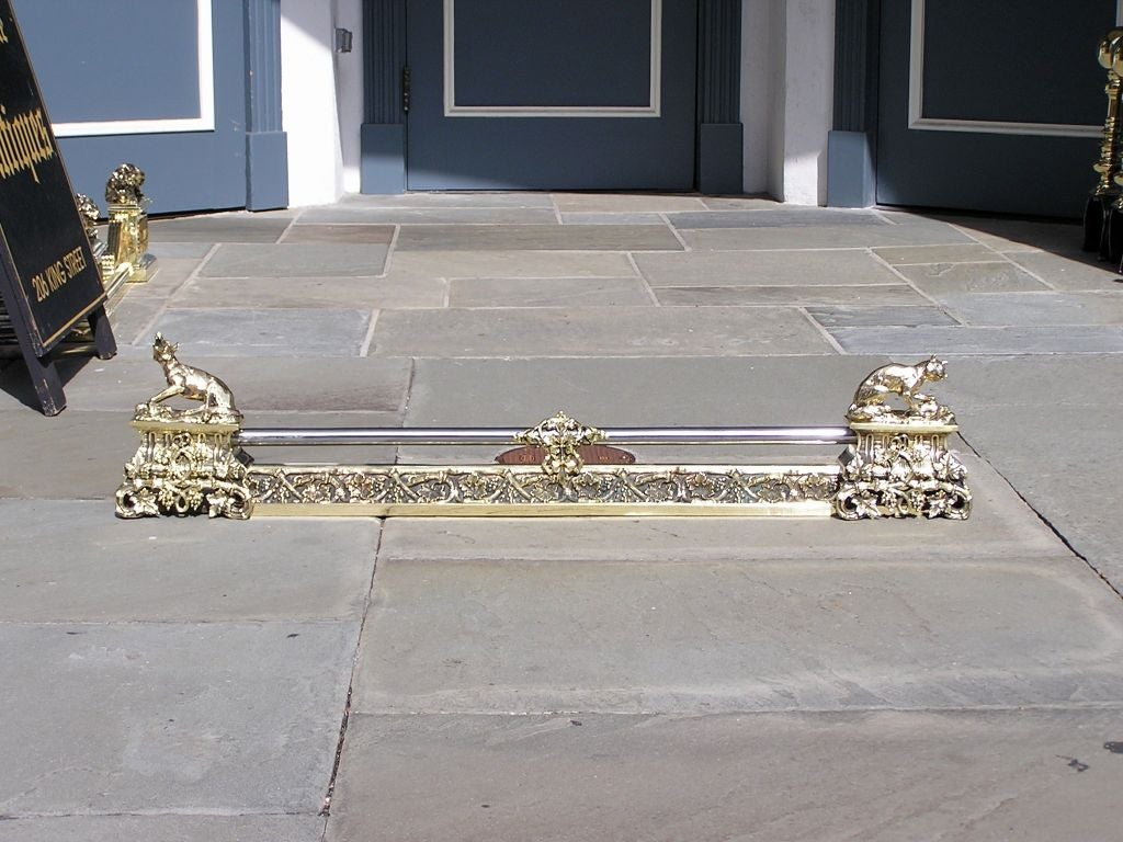 English brass and polished steel chenet with dueling foxes perched on ending plinths, hand chased with ivy, vine, and floral motif.