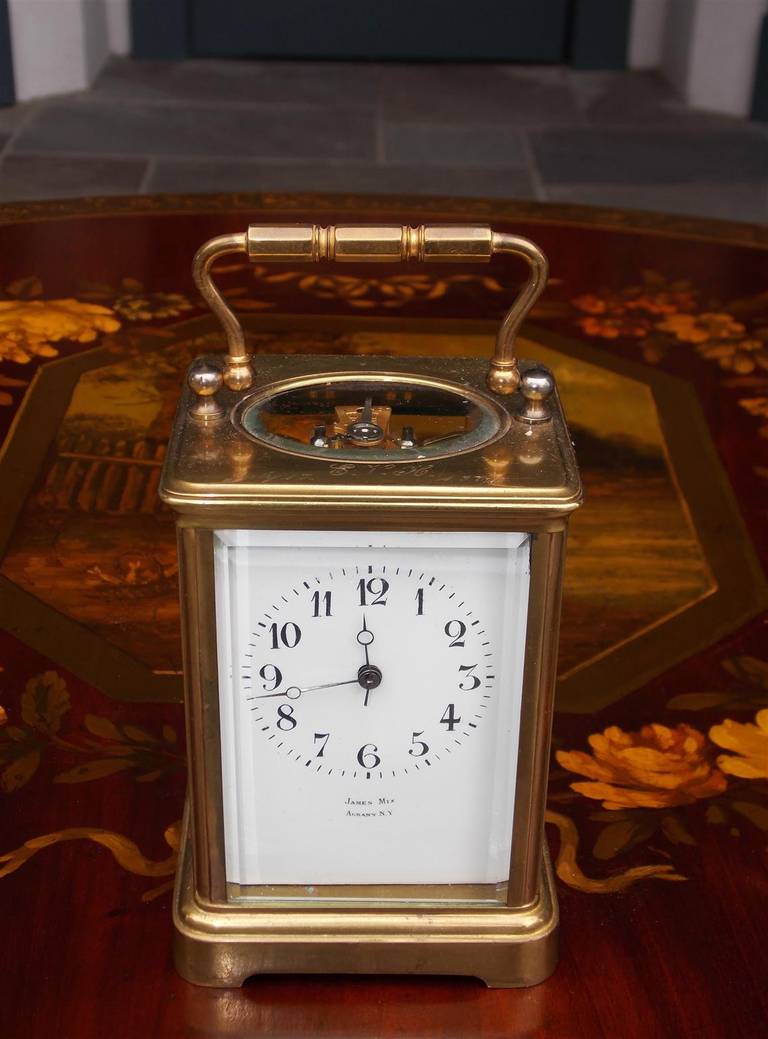 Orologio da carrozza in miniatura in ottone americano con vetro smussato, maniglia per il trasporto e quadrante in rame smaltato e firmato. L'orologio è composto da ora, suoneria e sveglia. L'orologio è stato prodotto da James Mix (1822-1907),