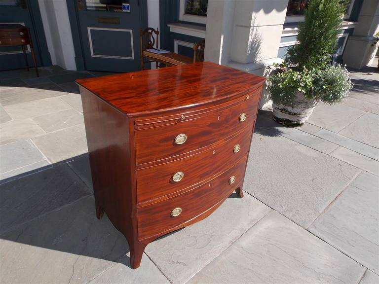English mahogany graduated three drawer bow front chest with original brushing slide, brasses, and splayed feet.  Late 18th Century