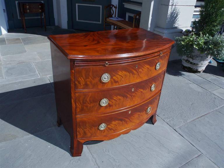 English figural mahogany graduated three drawer chest of drawers with original brushing slide, brasses, and splayed feet.  Circa 1780