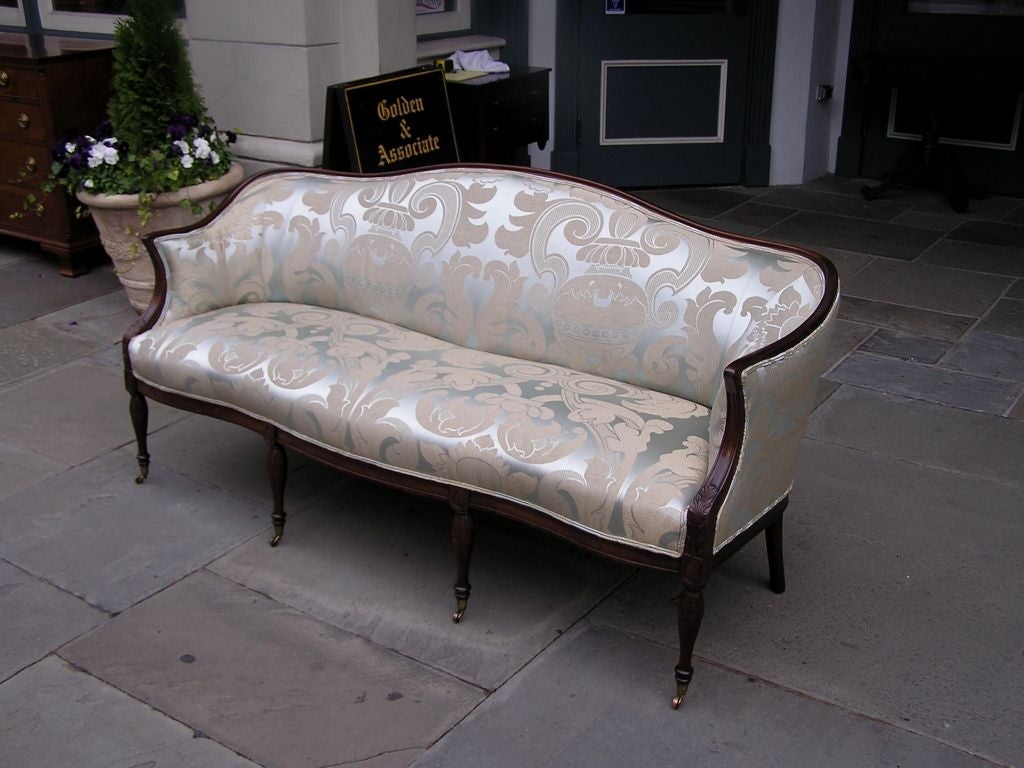 American mahogany sofa with serpentine shaped arms, carved acanthus knees, and terminating on  floral bulbous legs with the original brass casters. Boston, Mass. Late 18th Century