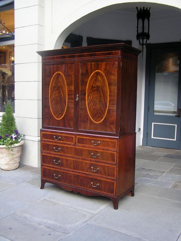 English Hepplewhite mahogany graduated five drawer linen press with oval satinwood inlaid hinged doors, pull out interior shelving, original period brasses, and ending on the original splayed feet. Late 18th Century