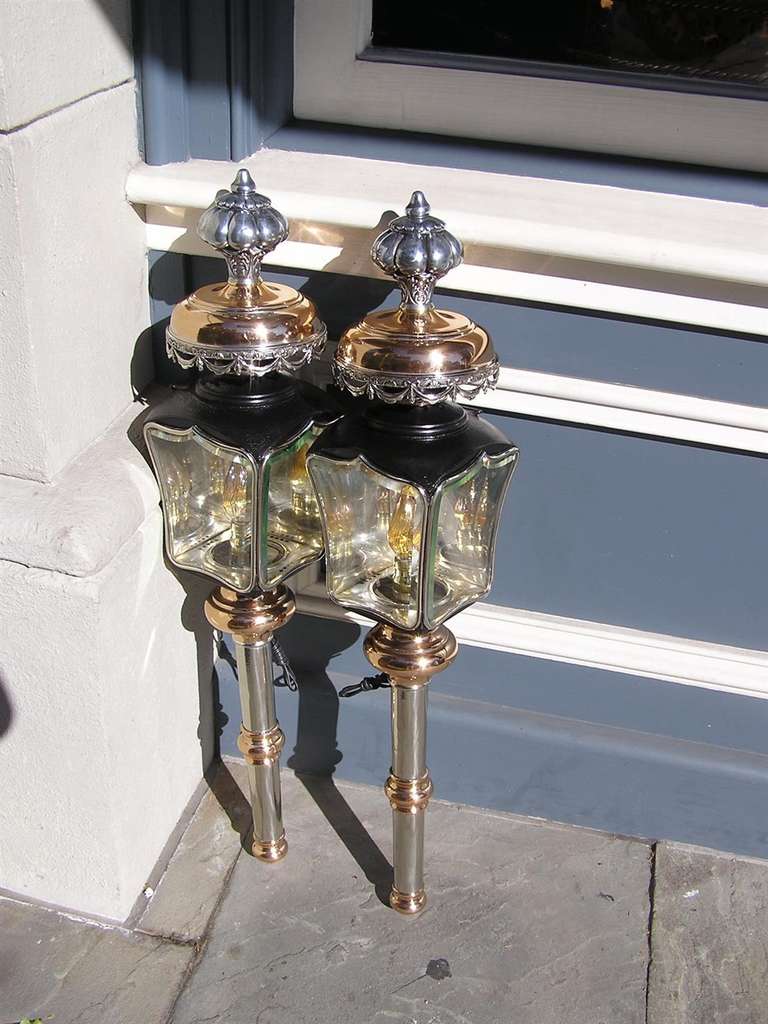 Pair of American nickel silver over copper & brass coach lanterns with bulbous melon finials, floral swag motif, and terminates on a turned bulbous ringed reservoir. Coach lanterns have the original beveled glass and have been electrified . Pair are