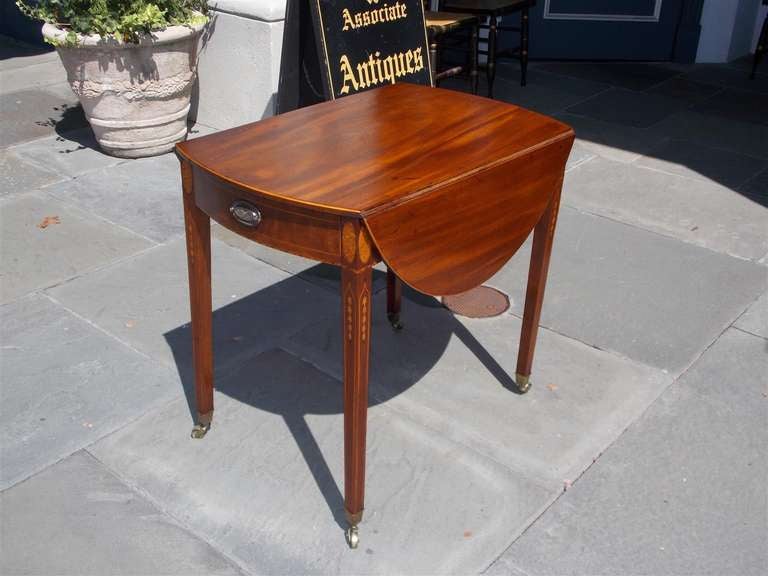 American Hepplewhite mahogany one drawer drop leaf pembroke with inlaid birds eye maple oval corners, satinwood string inlays, graduated bell flowers, and terminating on tapered legs with original brass cup casters. Late 18th Century, Rhode Island.  