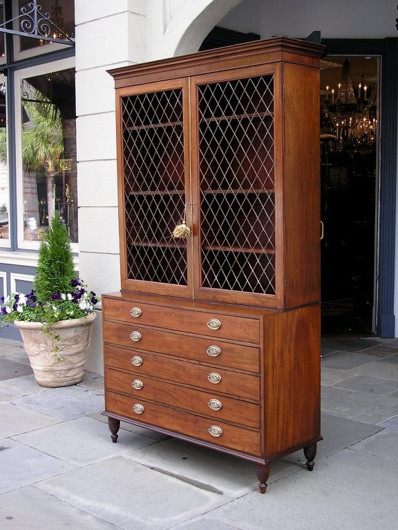 English Regency mahogany five drawer bookcase with upper case brass screened doors, adjustable shelving, and terminating on turned spiral feet.