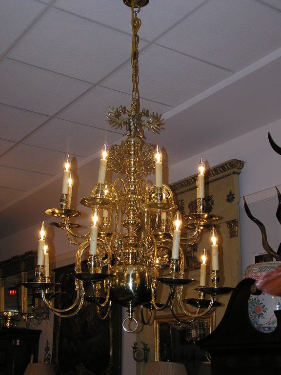 Dutch colonial Two tiered brass sixteen light chandelier with engraved double eagles, bulbous central column, removable pined scrolled arms with candle cup bobeches. and terminating with a brass ringed ball finial . Originally candle powered and has