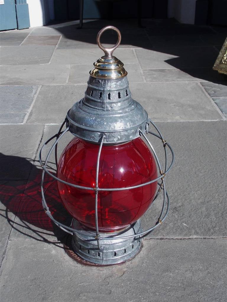 American brass cap onion lamp with galvanized protective cage surrounding the original ruby Perkins globe, . NY,  Early 20th Century