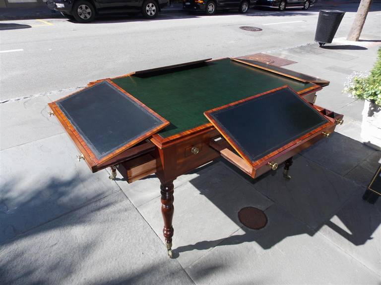 English Regency mahogany two-drawer drafting partners desk with centered leather top, four sliding adjustable hinged leather drawing surfaces, quill and inkwell flanking drawers, original brass pulls, and terminating on turned bulbous legs with