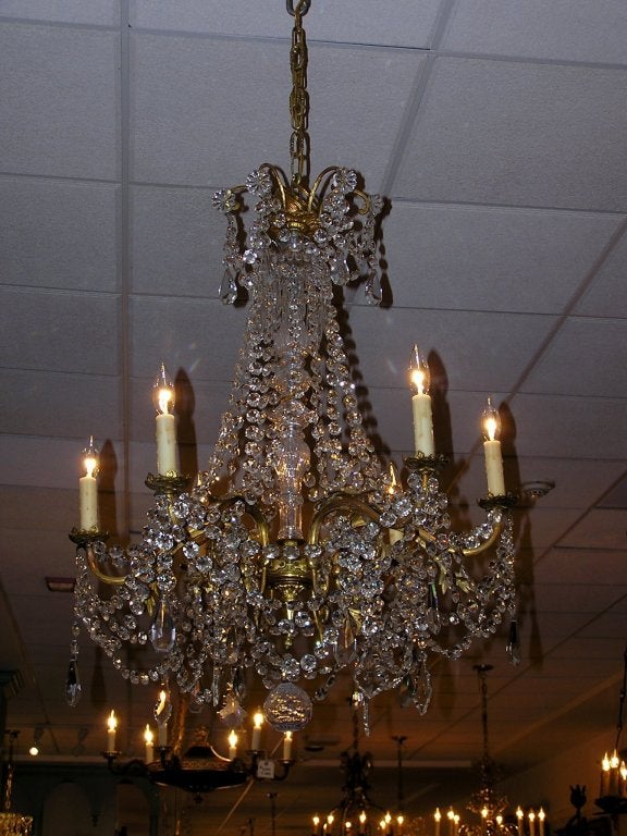 French gilt bronze and crystal six light chandelier with bulbous crystal center shaft and scrolled floral arms. Originally candle powered and has been electrified. Early 19th Century