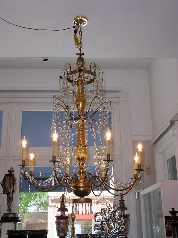 Pair of Italian gilt carved wood and crystal chandeliers with eight bronze arms. Originally candle powered and have been electrified. Late 18th Century