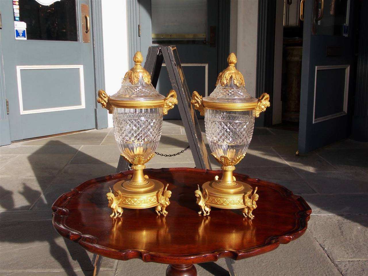 Pair of French ormolu and crystal compotes with artichoke finial tops. flanking Bacchus mounts, foliage motif, and terminating on round plinths with sphinx feet. Early 19th Century