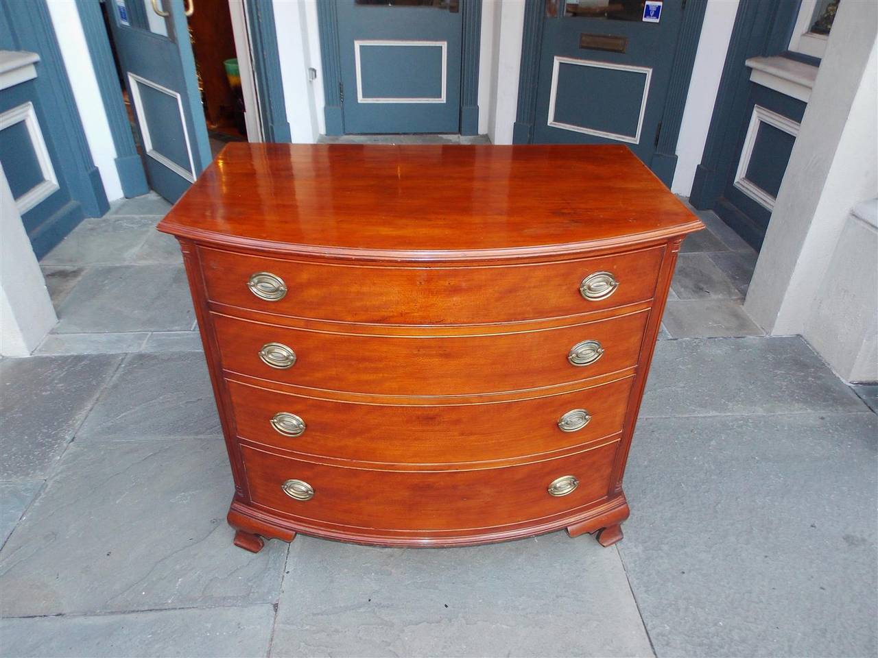 American Cherry bow front chest with carved molded edge top, four graduated drawers, original oval brasses, carved quarter columns, and terminating on original ogee bracket feet. Secondary wood consist of poplar.  Rhode Island. Late 18th Century

