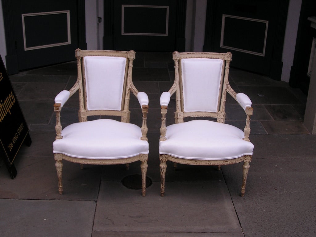 Pareja de sillones neoclásicos italianos pintados y tapizados, con medallones de follaje flanqueados, molduras incisas talladas, lengua de cordero, apoyabrazos bulbosos estriados y patas anilladas bulbosas estriadas en reposo, Finales del siglo