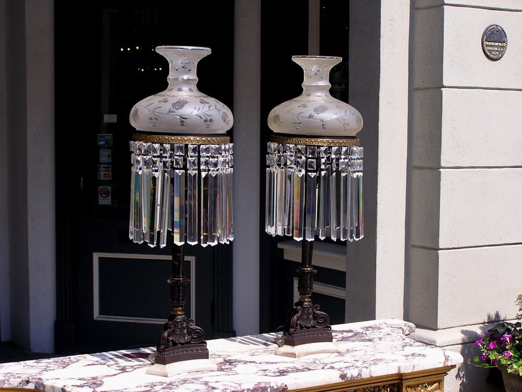 Pair of American bronze and crystal sinumbra table lamps with original etched frosted globes, centered Corinthian column, terminating on scrolled floral marble base. Originally oil and has been electrified.