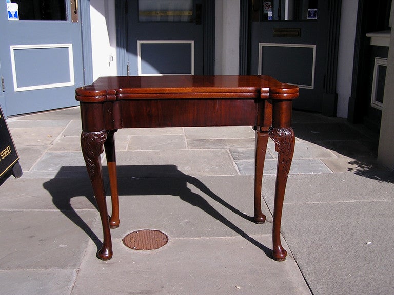 English Cuban mahogany one board flip top game table with carved rounded corners, supporting rear gate leg, acanthus carved knee, and terminating on pad feet. Dealers please call for trade price. 