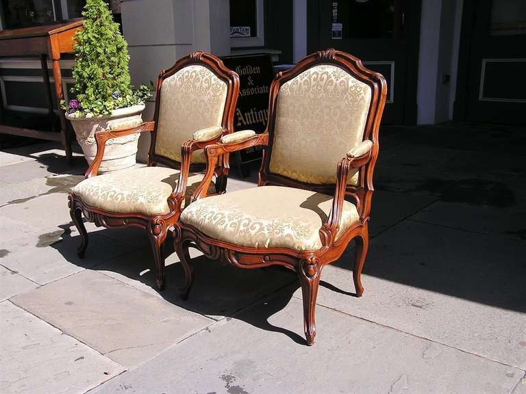 Set of four Italian upholstered walnut bergere chairs with carved scrolled floral motif and terminating on cabriole legs.  Circa 1790.  Will separate into pair if desired.