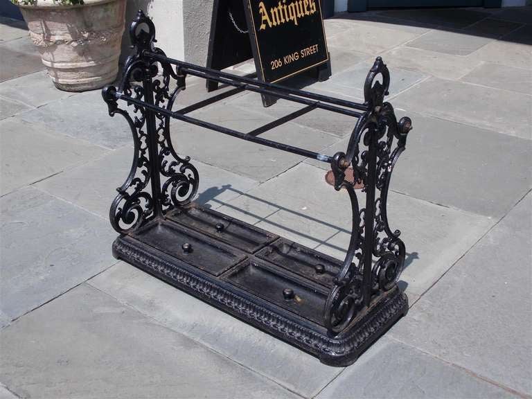 English cast iron umbrella / cane stand with three section top, scrolled floral side mounts, four removable pans, and terminating on decorative cast egg and dart base.