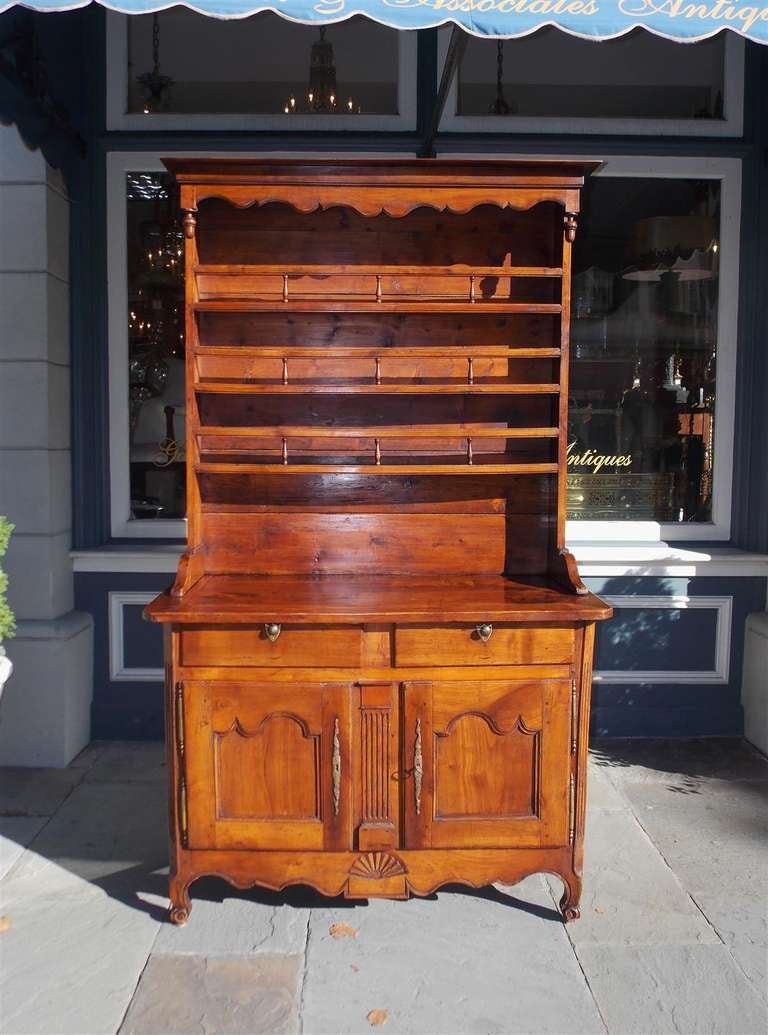 French cherry step back two drawer cupboard with carved acorn finials, gallery shelving, lower two door cabinet, and terminating on stylized cabriole legs.