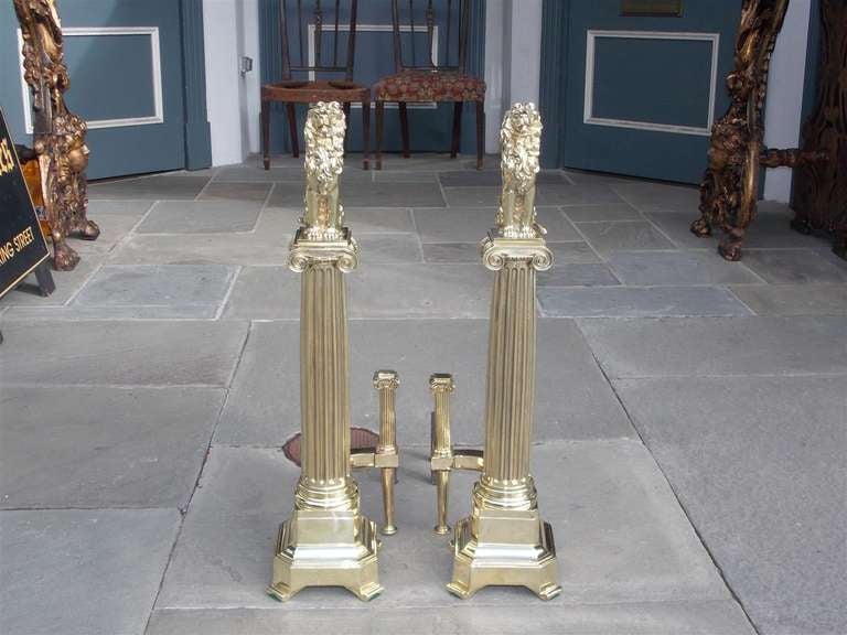 Pair of English Brass Monumental Lion Andirons on Corinthian fluted plinths, matching log stops, and terminating on squared scrolled base.