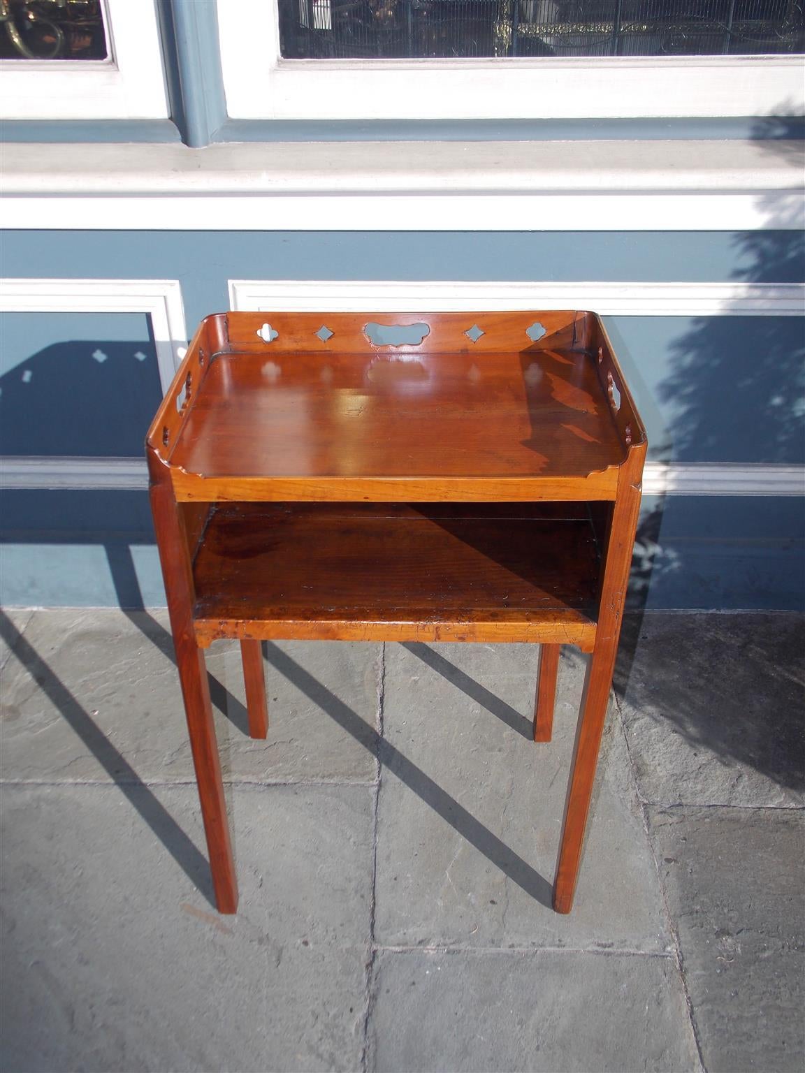 English Chippendale mahogany side table with carved decorative  pierced gallery, interior open cupboard, and terminating on tapered square legs.  Late 18th Century