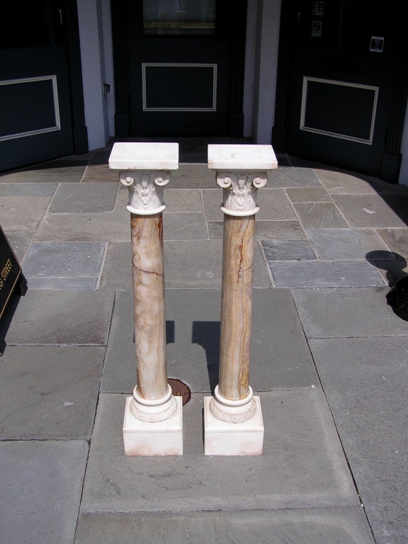 Pair of Italian Corinthian hand carved marble pedestals with decorative bell flowers & laurel wreaths, centered turned ringed pedestals, and terminating on the original squared lower plinths. Early 19th Century