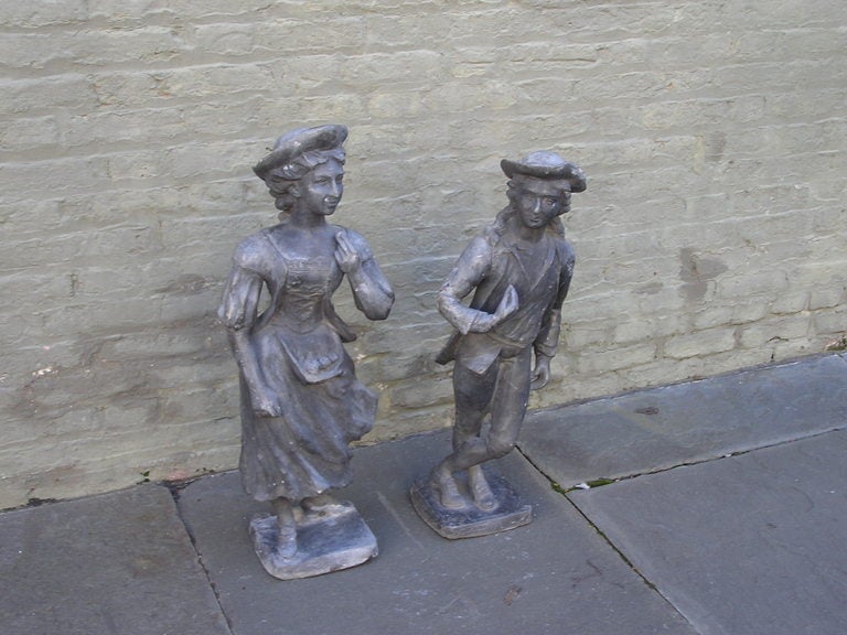 Pair of English lead garden statues of girl and boy standing on squared plinths.  
