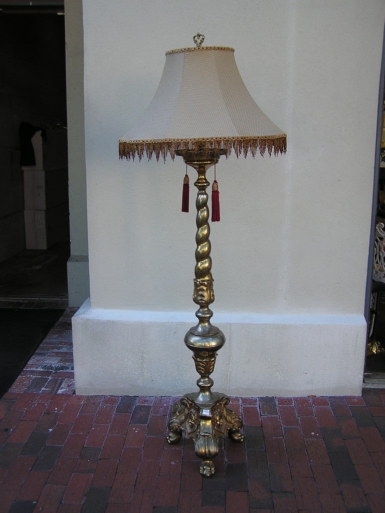 Lampadaire à deux lumières en bronze doré français, avec une tige torsadée à volutes, reliée à une urne inférieure à bulbe floral, et se terminant sur une base tripode à griffes florales avec une figure décorative.  Les concessionnaires sont priés