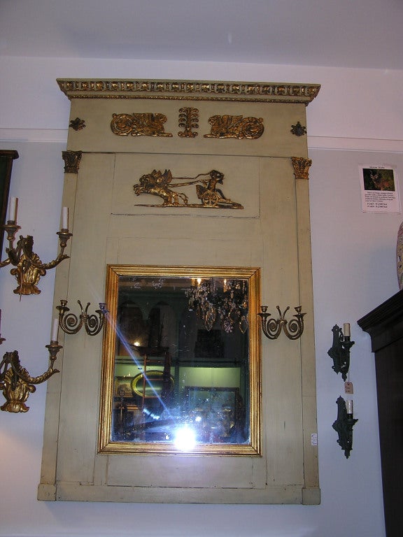 French painted and gold gilt trumeau mirror with resting griffons, chariot, gilt bronze sconces, and carved gilt floral motif. All original