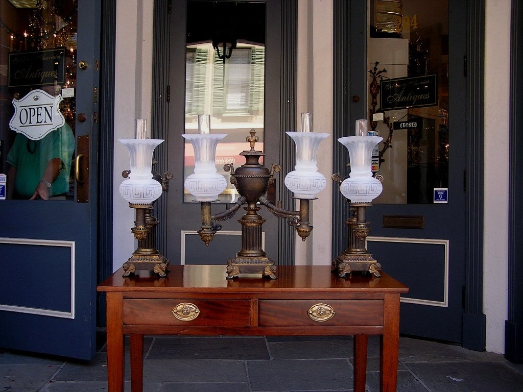 Set of three American gilt bronze argand lamps with centered floral urn, fluted circular plinth, each terminating on squared bases with cherub feet motif. Original condition, never been electrified. Can be converted to electricity if desired.