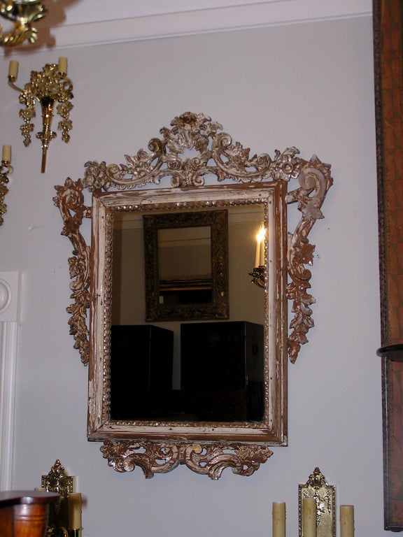 Italian carved wood, gesso, painted, and silver gilt mirror with shell and scrolled floral decorative work. All original