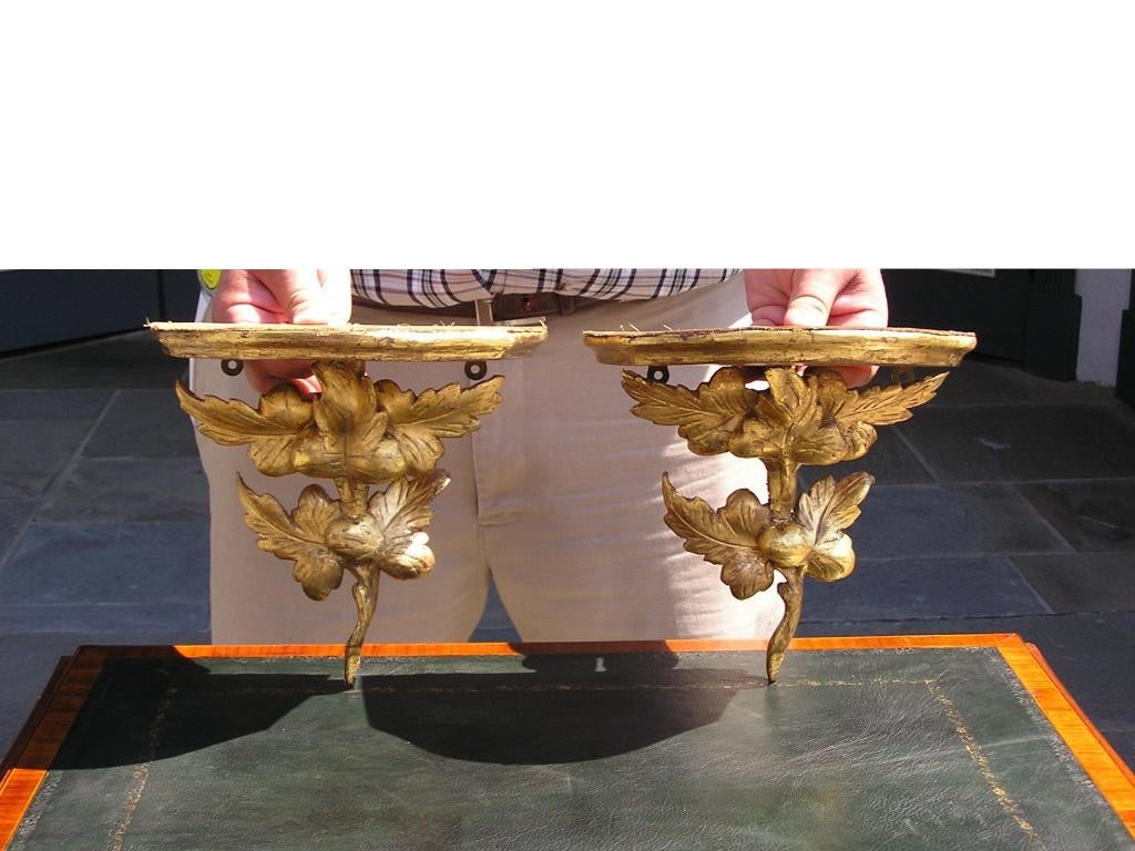 Pair of American carved wood and gesso gilded wall brackets with demi-lune molded edge and carved Oak leaf floral motif.  Dealers please call for trade price.