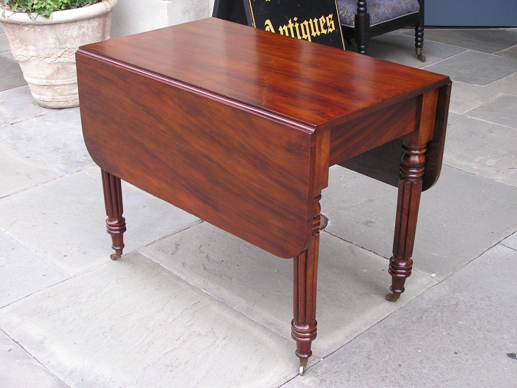 American Federal mahogany drop leaf  breakfast table with a one board top, two drop leaves, and terminating on turned reeded ring legs with the original brass casters, Baltimore. Early 19th Century