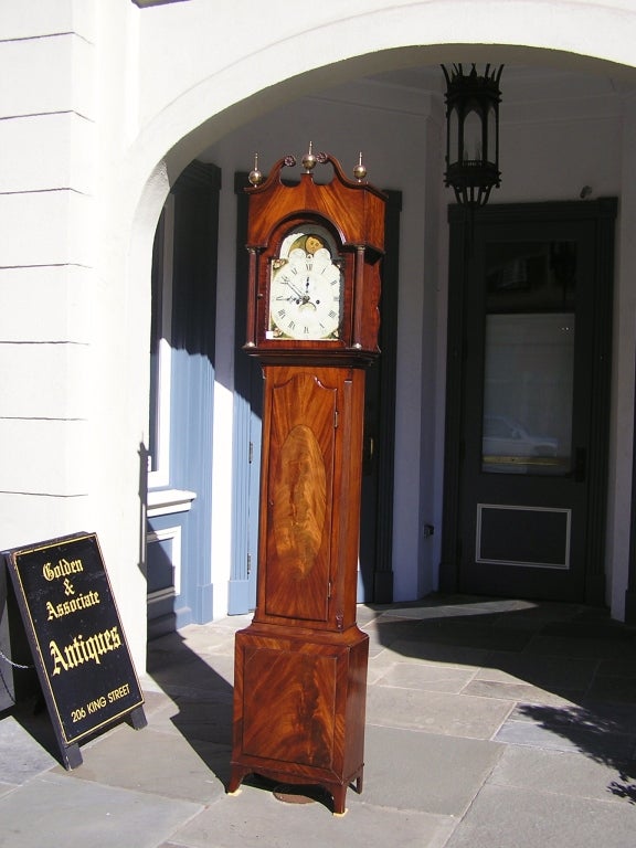 American Hepplewhite mahogany eight day tall case clock with arched swan neck bonnet, carved rosettes, brass finials, fluted columns, lunette moon phase, shell painted spandrels, oval crotch mahogany inlaid trunk, terminating on thumb molded squared