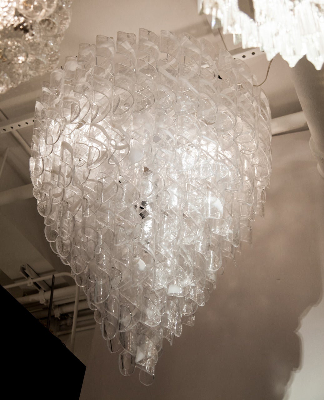Individually sculpted clear and white handblown Murano glass spirals make up this elegant chandelier. Each handmade glass piece is partly covered by an opaque white line over transparent glass. The white color is very pure when it is lit. Chromed