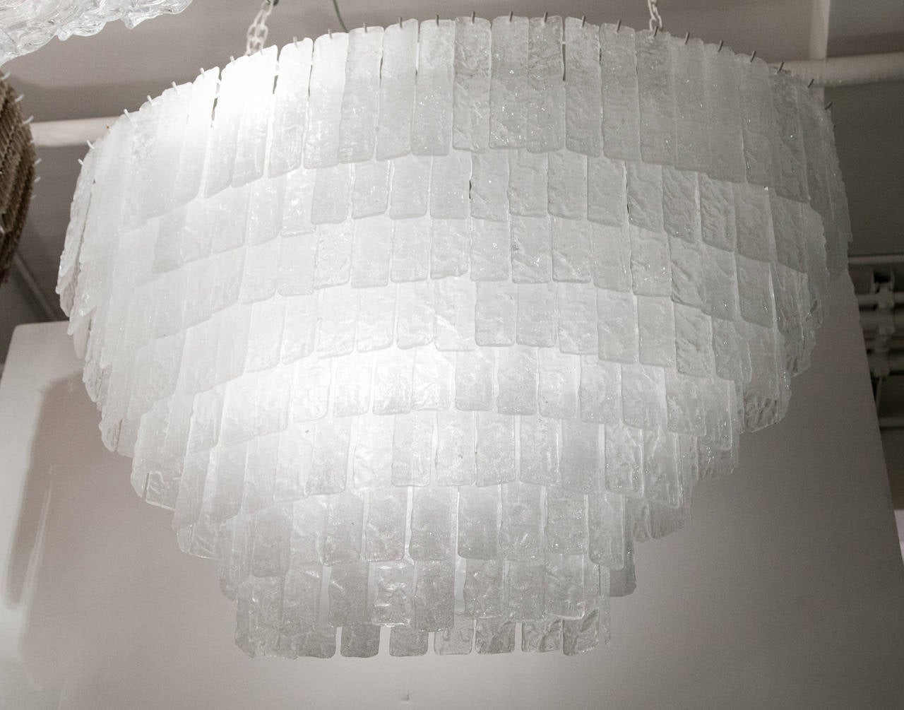 This chandelier is simply superb. Comprised of over 100 individual handblown rectangular clear Pulegoso glass pendants suspended from a white oval frame. Pulegoso glass refers to glass containing numerous bubbles (