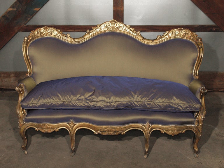 This piece is absolutely gorgeous and one of a kind. Completely restored and upholstered in a thick iridescent silk taffeta which changes from a rich grey to a purplish or plum color depending on the light. hand-carved giltwood (gold) frame with