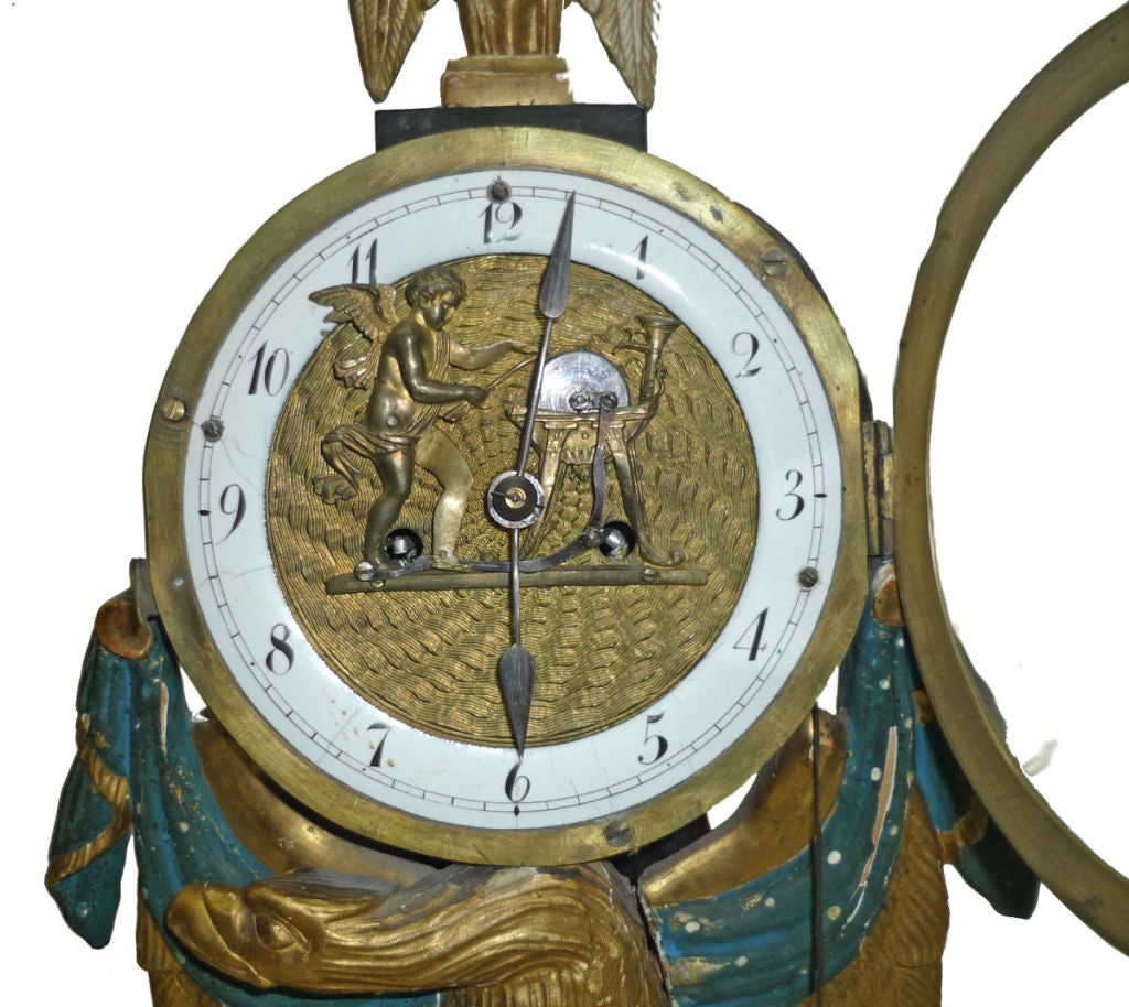 with an Automaton Dial; drum case with eagle finial and supported on an eagle, with mounts to the front and raised on a bow fronted plinth with turned feet. The ormolu dial with white enamel Arabic chapter ring and centred by an automaton figure of