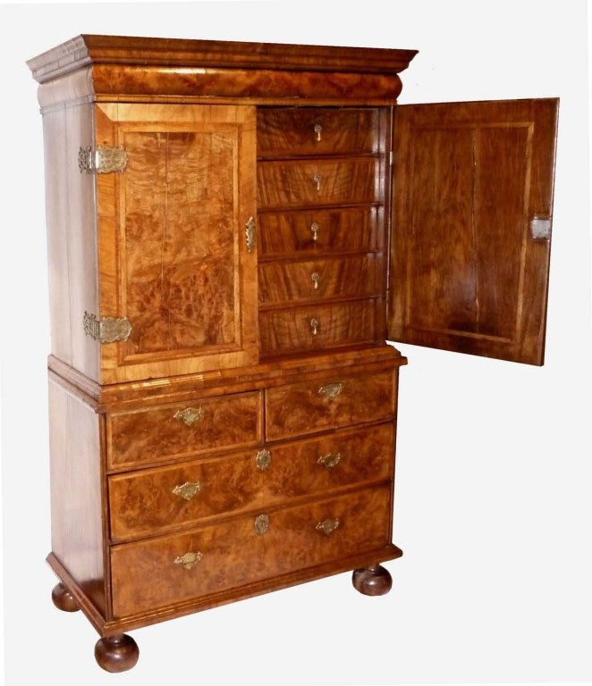 molded cornice over a cushion drawer frieze above a pair of cabinet doors opening to a fitted interior; the base with two short over two long drawers; raised on bun feet. Secret Compartments.
