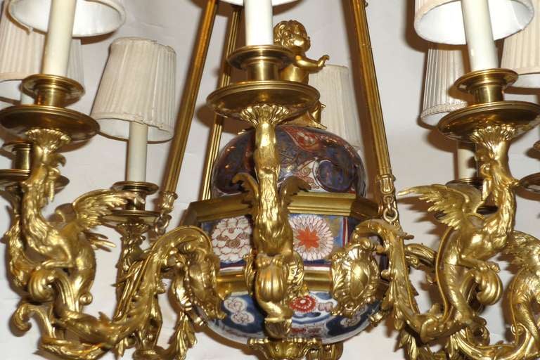 Rare Louis XV Style Bronze Dore and Imari Eight Light Chandelier, Circa 1860-80; Chinese pagoda shielding a cherub sitting on a rocaille base supported with an imari cover and bowl; with eight dragons emerging from a cartouche and supporting the