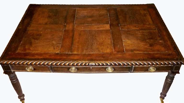 Paneled top with a gadrooned edge over a frieze with three drawers on each side; raised on turned and tapering reeded legs ending with brass casters.