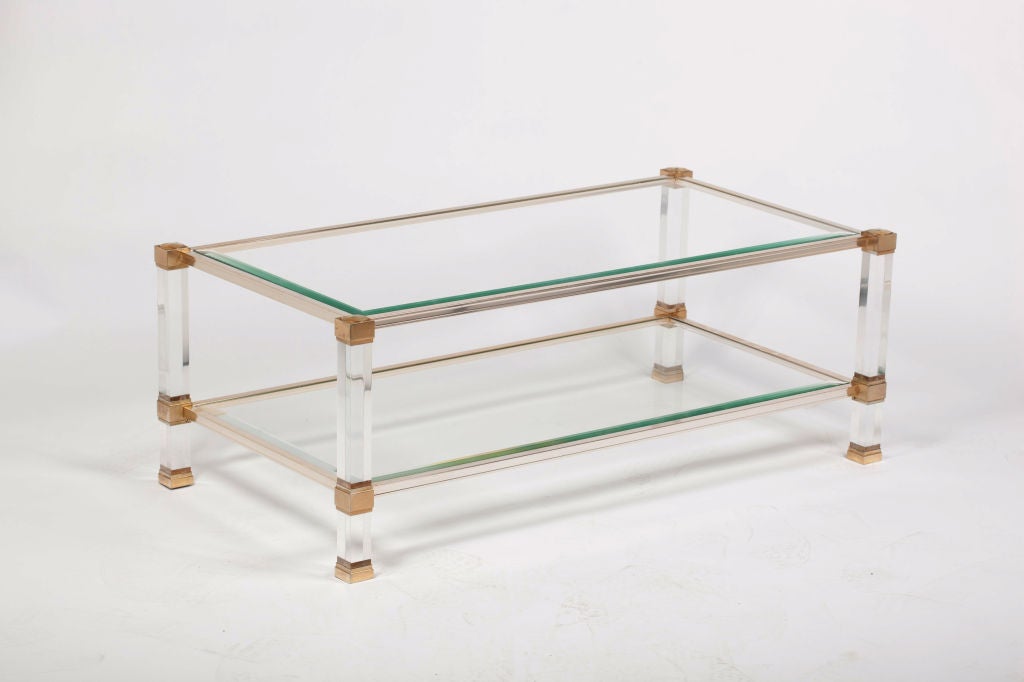 A lucite, glass and brass coffee table created in France in the 1980s has geometric lines that include substantial square legs with brass accents. It is signed Pierre Vandel Paris.